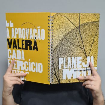 Vestibulanda segurando o Caderno de estudos Planejamente em frente ao rosto.